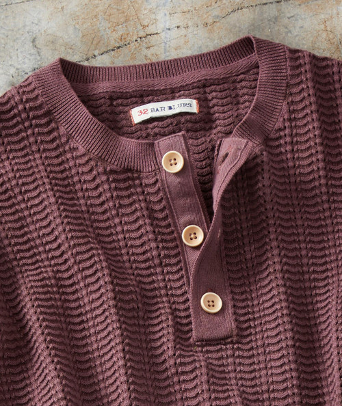 The Way It Goes, a maroon knit cardigan with textured cable patterns, beige buttons, and a ribbed collar and placket.
