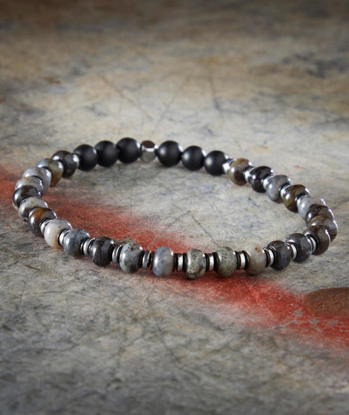 Skippin' Stones bracelet, beaded bracelet with black, gray, and white stones and metallic accents on a stone surface.