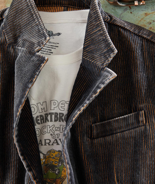 Groove Me, close-up of a stylish zip-up jacket with dark fabric and fine orange and grey pinstripes over a white T-shirt with graphic print.