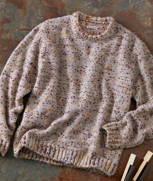 Bit By Bit, cozy multicolored speckled sweater laid flat on a textured surface.