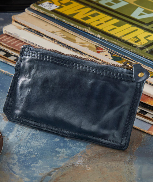 Quest For Coin, black leather zipper pouch placed on a surface with magazines or books in the background.