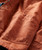 32 Bar Blues Please Do Something, close-up of a brownish-orange garment with a large pocket and detailed stitching.