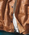 32 Bar Blues Ramblin' Jack, close-up of brown leather jacket with black buttons and a white inner lining.