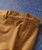 32 Bar Blues Bend One, close-up of brown fabric pants showing belt loop and zipper details.