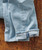 32 Bar Blues Take Me Back, close-up of light blue denim jeans with rolled-up cuffs on a wooden surface.