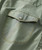 32 Bar Blues The Scene Is Clean, close-up of a green fabric shirt pocket with a button and yellow stitching detail.