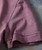 32 Bar Blues Who's Got Rhythm? T-shirt, close-up of the pink fabric with black stitching details.