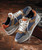 32 Bar Blues I Walk A Little Faster, stylish men's sneakers with a color block design in brown, navy blue, gray, and orange accents on a rustic wooden surface.