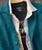32 Bar Blues The Shifting Scene, close-up of layered clothing including a teal blazer, a striped inner shirt, and a black T-shirt with designs, showing the textures and layers of the fashion ensemble.