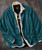 32 Bar Blues The Shifting Scene, a stylish men's outfit featuring a teal blazer, a layered shirt, and a graphic T-shirt.