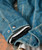 32 Bar Blues Just Like That, close-up of a denim jacket cuff with metal snap buttons and layered fabric showing its style and texture.
