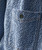 32 Bar Blues Jumpy Blues, close-up image of a textured fabric shirt with a patterned weave, featuring a single pocket and a black button.