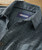 32 Bar Blues Sticks & Strings, a close-up image of a stylish men's dress shirt with a classic checkered pattern in shades of gray and black, featuring a contrasting label inside the collar.