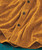 32 Bar Blues Gold Fever, close-up of a textured orange fabric with detailed embroidery and black buttons.