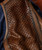 32 Bar Blues Hello Number One, close-up image of a brown leather jacket with a woven texture panel and a zipper detail.
