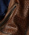 32 Bar Blues Hello Number One, close-up image of a textured brown leather product with a detailed woven pattern and a black zipper.
