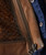 32 Bar Blues Hello Number One, close-up of brown leather jacket with woven leather detail and visible zipper.