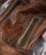 32 Bar Blues Hello Number One, close-up of a brown leather bag with a woven leather section and a front zipper pocket.