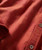Better All The Time, close-up of a rust-colored fabric shirt with a subtle diamond pattern and white buttons.