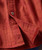 Better All The Time, close-up image of a rust-colored checkered shirt with a button and visible stitching.