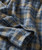 Blue Soul, close-up of a plaid patterned fabric shirt with blue, beige, and gray colors, featuring button details.