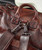 Destination Anywhere, close-up of a brown leather travel bag with sturdy handles and a metal clasp securing a detachable shoulder strap.