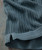 Vertical Man, close-up image of a gray knitted fabric with vertical stripes and a ribbed hem, showing detailed texture and stitching.