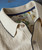 Cast Away, close-up image of a beige collared shirt with a textured ribbed pattern, featuring white buttons and a navy blue trim on the collar and placket.