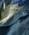 Blazin', close-up of layered casual men's shirts, featuring a blue denim shirt over a patterned yellow-green shirt with a button detail.