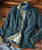 Blazin', men's multicolored layered casual outfit with a navy blue jacket, green and blue shirt, and white t-shirt, displayed on a rustic wooden surface.