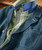 Blazin', a layered clothing product, featuring a blue denim jacket with a front pocket and a bold lapel, combined with a light green and blue mesh-lined shirt underneath.