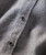 Black And Tan, close-up image of a textured fabric shirt featuring small checkered patterns and black buttons.