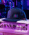 This Note's For You, black baseball cap with embroidered logo featuring a pink and blue design, placed on amplifier in a concert or musical setting.