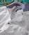 32 Flavors, a men's button-down shirt with a white base and multicolor small printed patterns, featuring a contrasting blue denim collar and brown buttons.