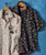 Papa's Gettin' Hot - Tan, stylish men's shirt with floral pattern, one in light beige and dark beige, hanging on hangers against a blue background.