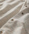 On The Dot, close-up of a beige patterned shirt with small multicolored dots and buttons.