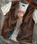 Rad Gumbo, vintage brown leather vest over a white vintage band T-shirt with red and blue print.