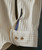 I Dug Up A Diamond, close-up of a textured beige quilted jacket sleeve with two beige buttons and a dark ribbon detail.