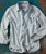 River Of Blues, Light blue men's button-up shirt with striped inner collar and cuffs, chest pocket, laid flat on textured background