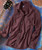 Do Your Own Thing, maroon plaid button-up shirt with a front pocket, laid on a textured multicolored background with a guitar partly visible.