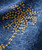 Palm Wine, close-up of detailed golden embroidery on denim fabric.