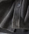 Whatever It Takes, close-up of a clothing fabric with a button, showing textured dark gray, ribbed fabric detail.