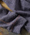 Thump And Bump, close-up of a textured, stretchy, gray thermal shirt fabric with visible stitching on a wooden surface.