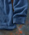 Very Yes, blue knitted sweater with textured ribbed pattern and ribbed cuffs, laid out on a rustic surface.