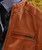 Make My Getaway Leather Jacket, close-up of a brown leather jacket with a zippered pocket and detailed stitching.