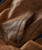 Watch Me Gone, close-up of a brown leather bag pocket with detailed stitching and textured surface