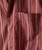 Red Arrow, close-up of a textured red fabric shirt with white arrow and dotted stripe pattern, featuring a chest pocket and white buttons.