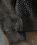 Need More, close-up image of a textured charcoal black knit sweater with ribbed cuffs and a chunky hook-knit pattern.