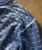 Drifting Blues, detailed close-up of a knitted blue sweater with a textured checkered pattern.