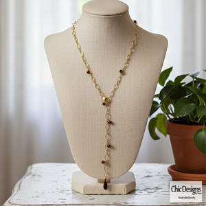 Garnet Y Lariat Necklace sitting on a mannequin necklace form on white distressed table